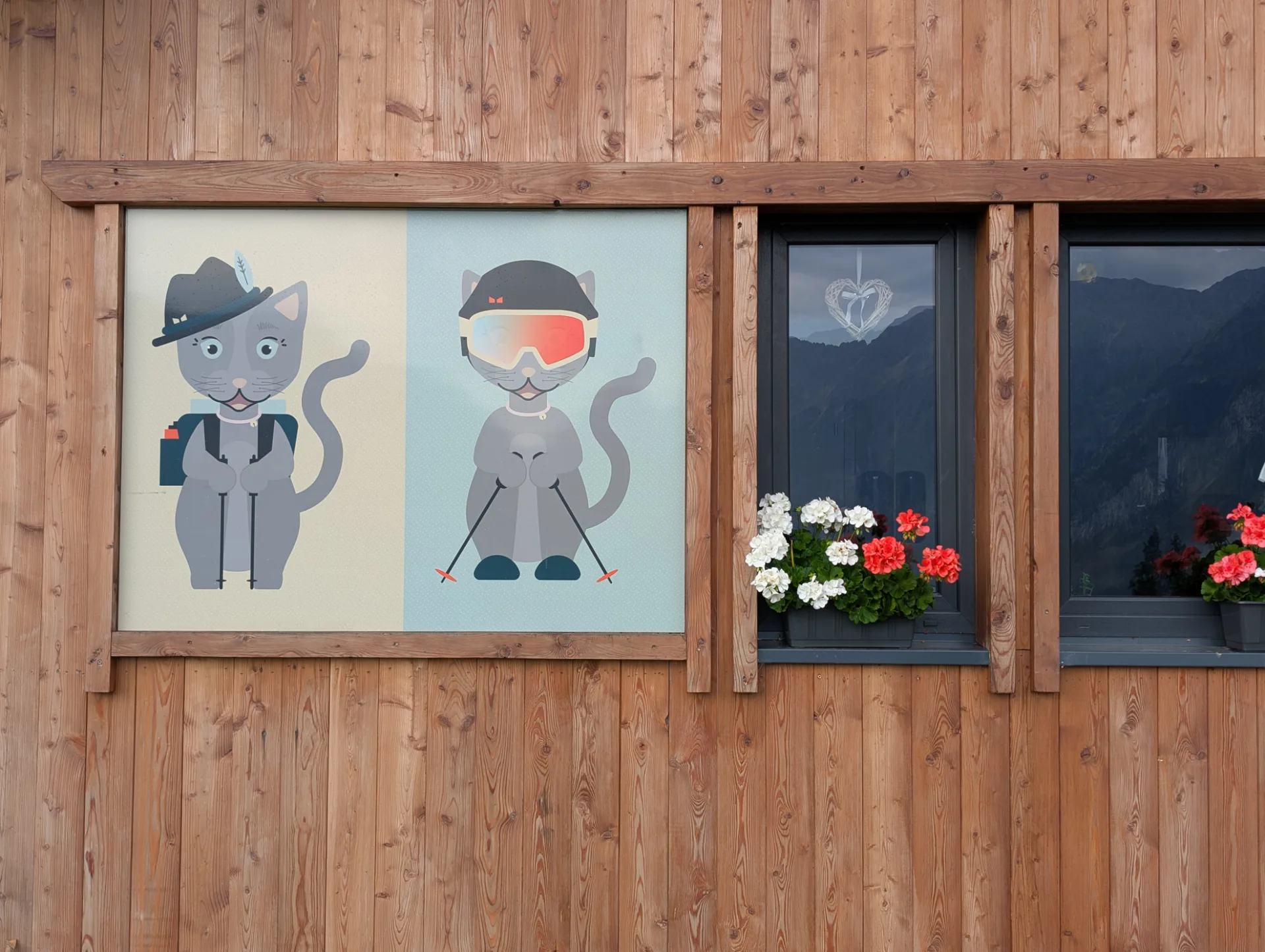 Tyrolean cartoon-cat wall plaques with geraniums