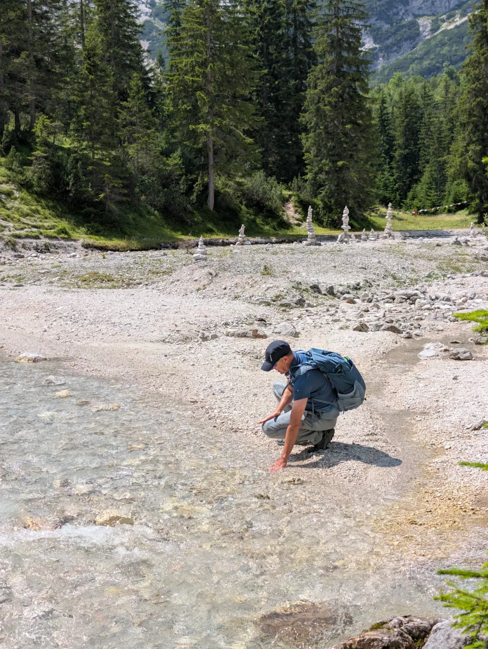 A hiker by the stream with cairns