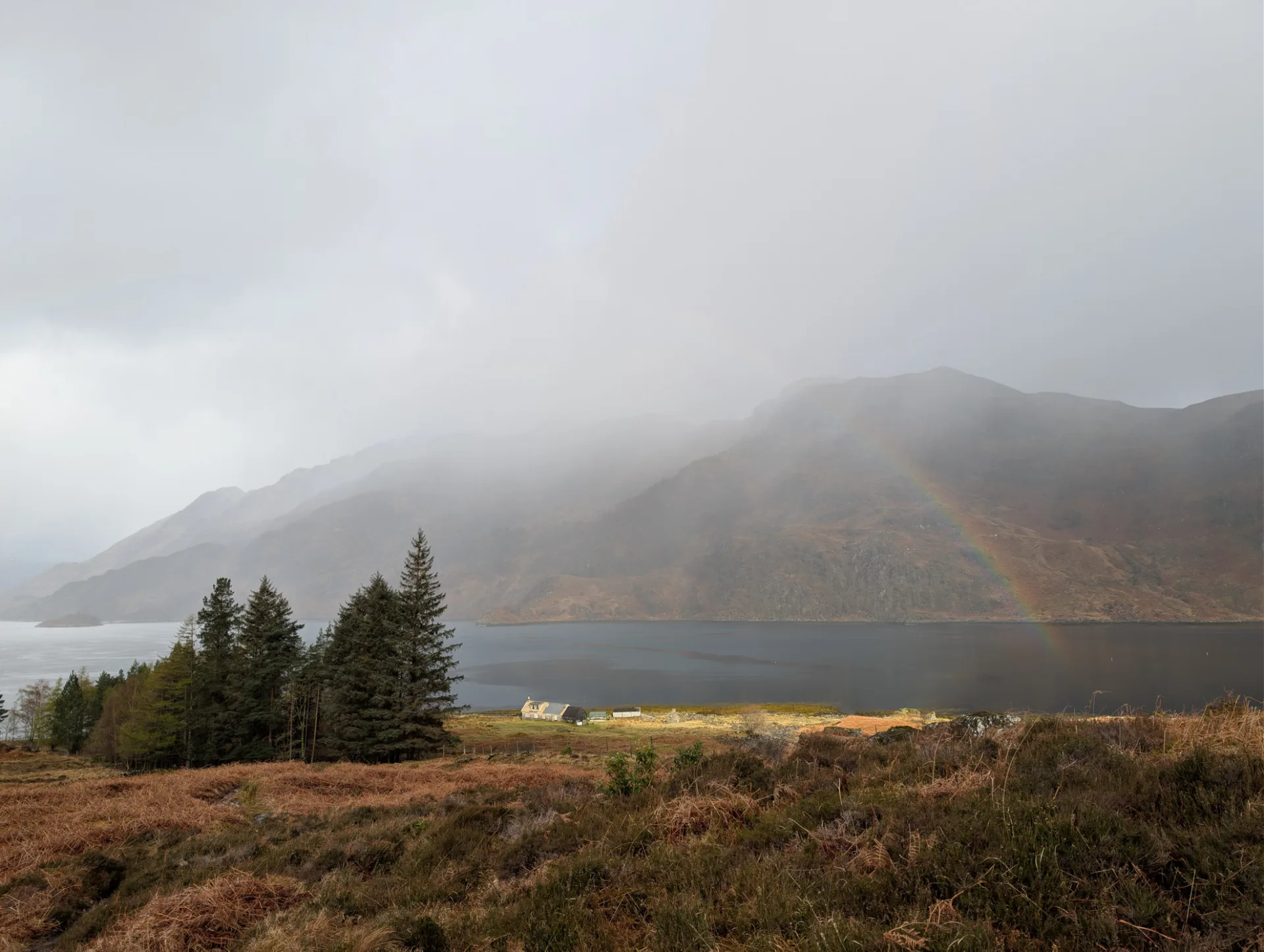 Rainbow over the loch, a solitary house on the shore