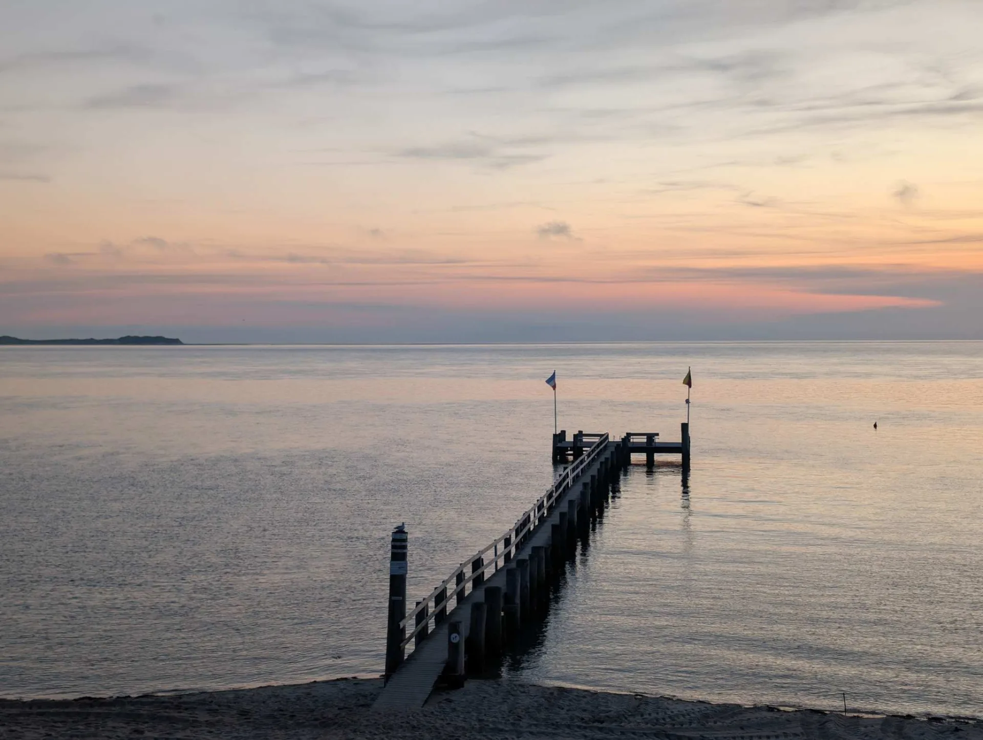 The Utersum bathing jetty in the evening light, Amrum's silhouette on the horizon.