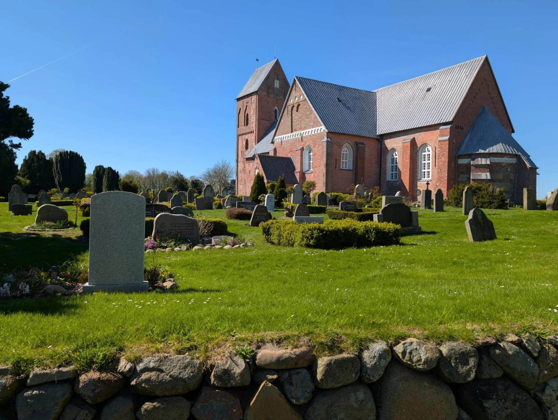 St. Johannis in Nieblum, the 'Frisian cathedral' — one of Föhr's great medieval brick churches, its old Frisian graveyard behind the fieldstone wall.