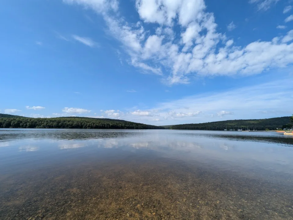 A wide view across the Lac des Vieilles Forges, the first sailboats moored along the shore.