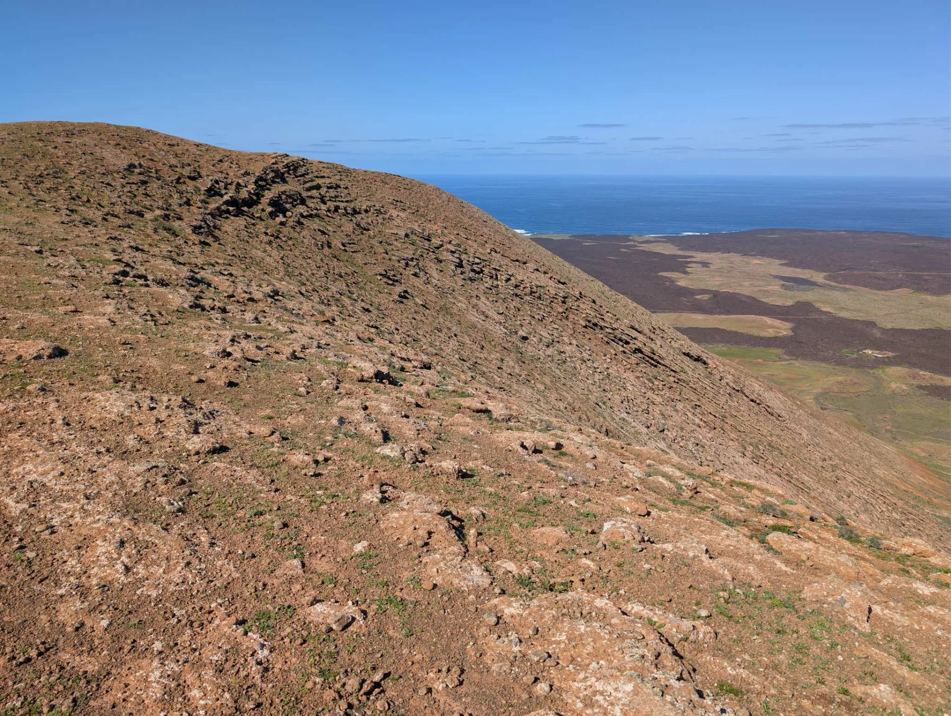 Up the ochre flank — the sea glinting on the horizon.