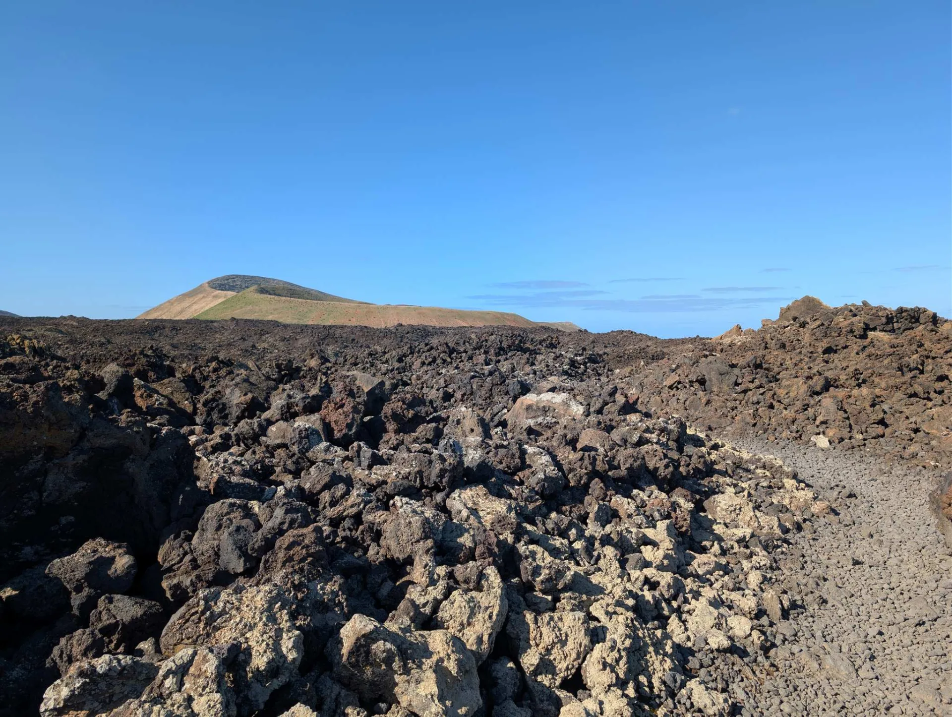 A path crosses the lava field, volcanic cones all around.