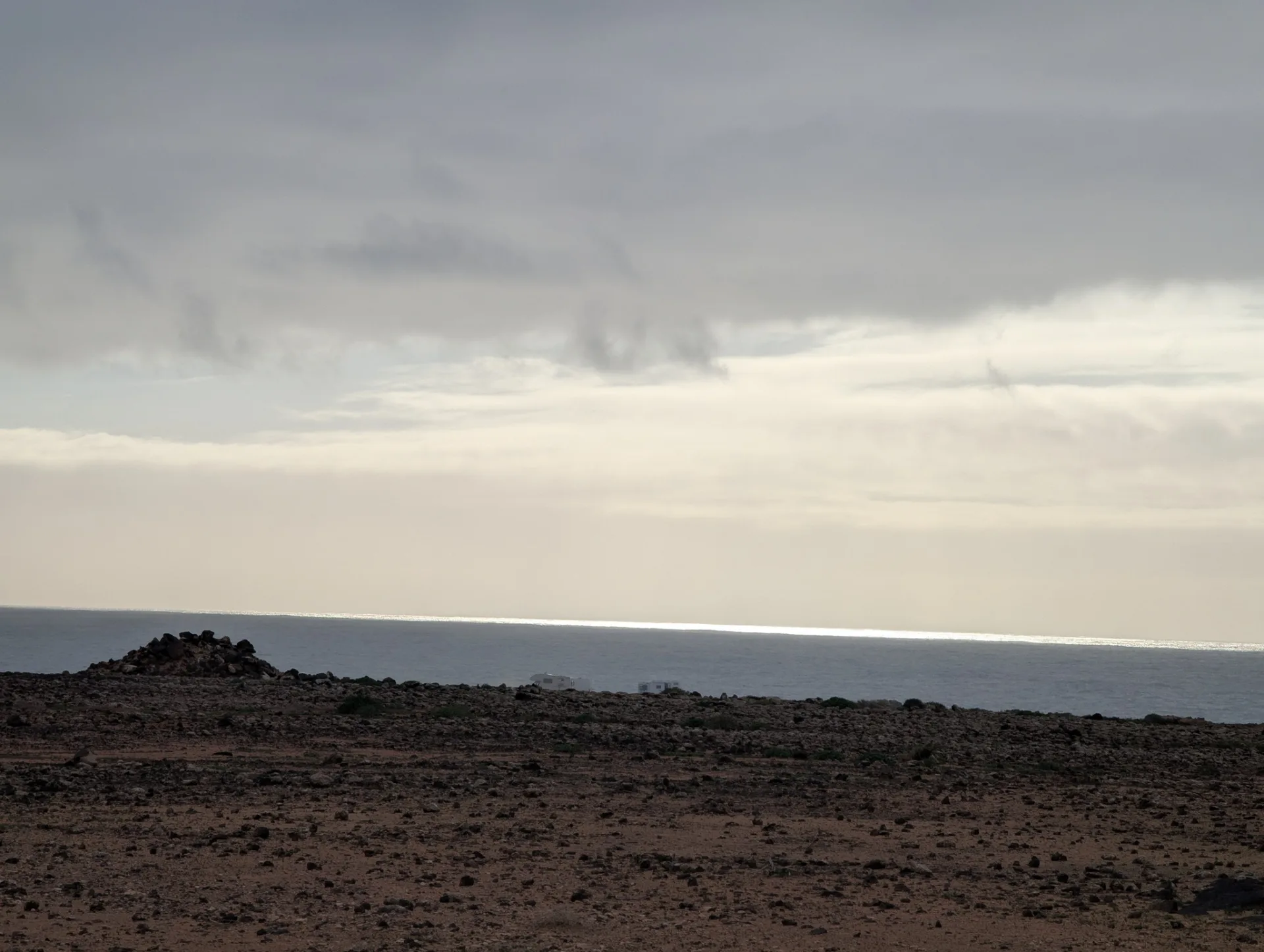 A wide lava plain by the coast under a heavy sky.