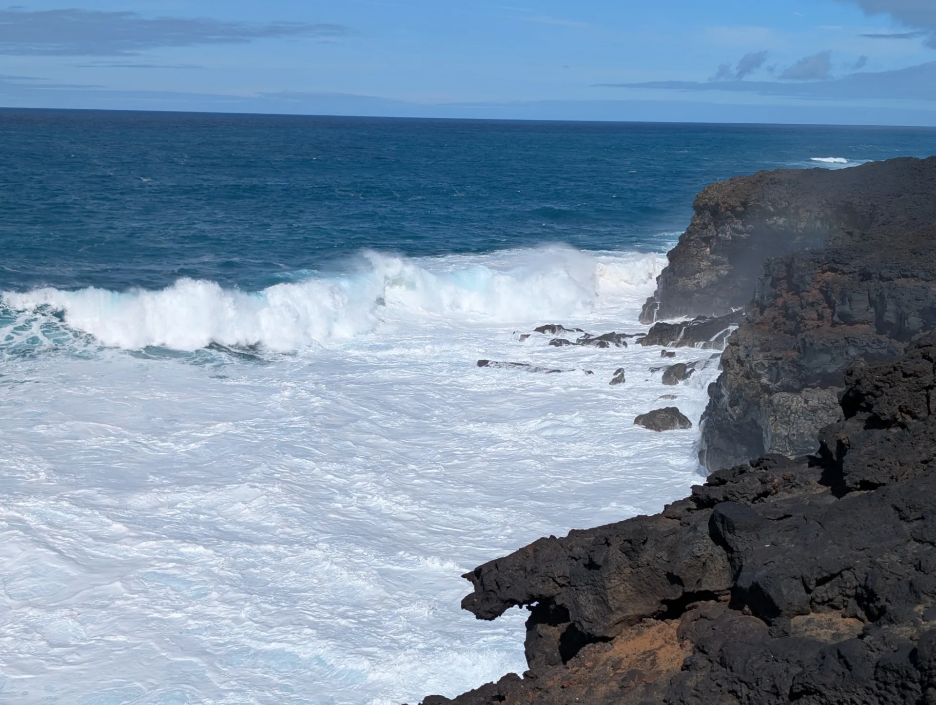 Heavy waves break against the black rock.