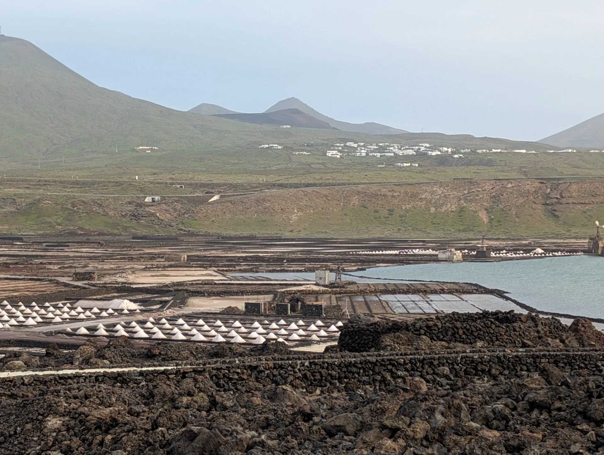 The salt pans stretch in geometric basins down to the sea.