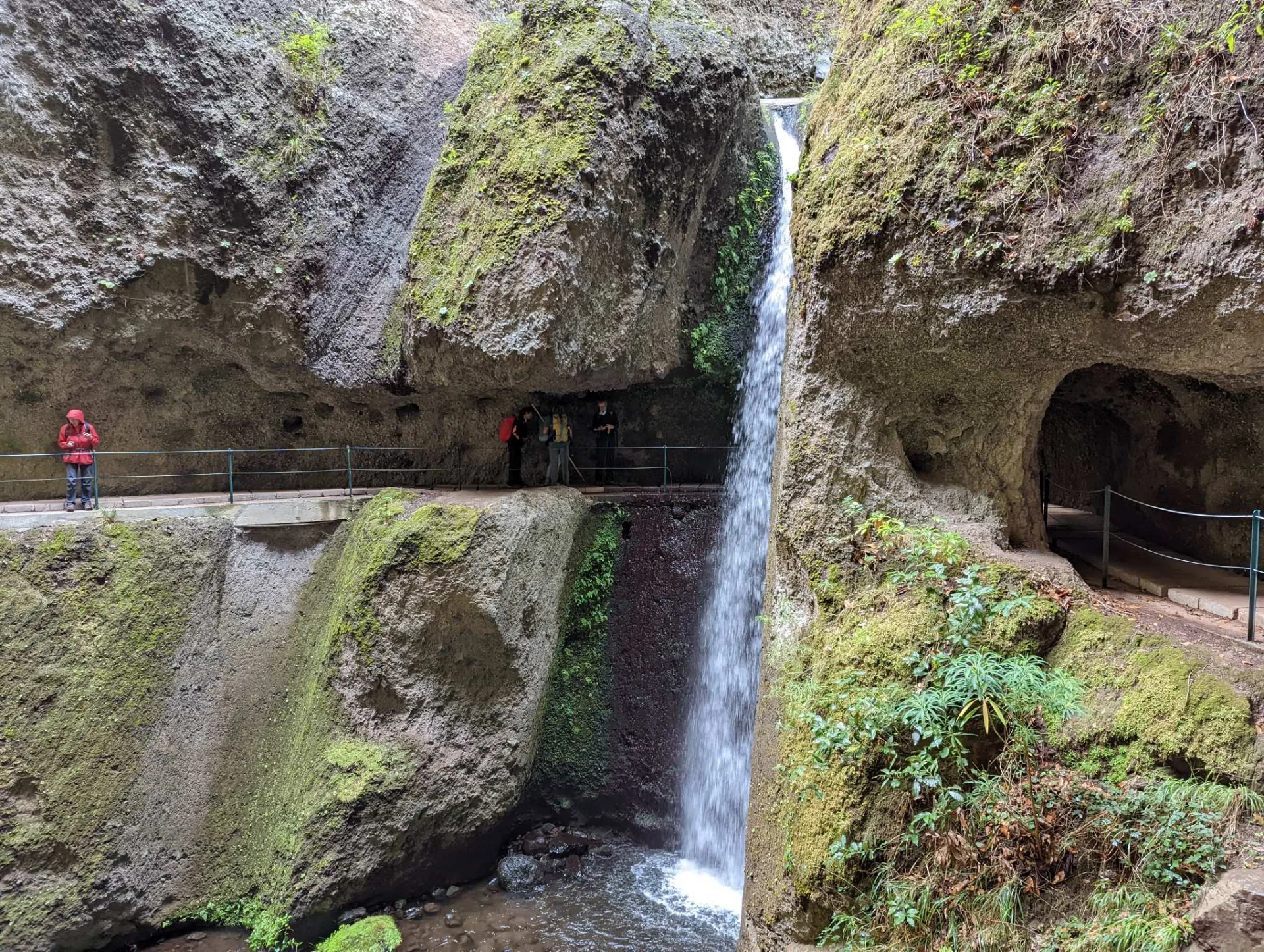 A waterfall over the levada path cut into the rock