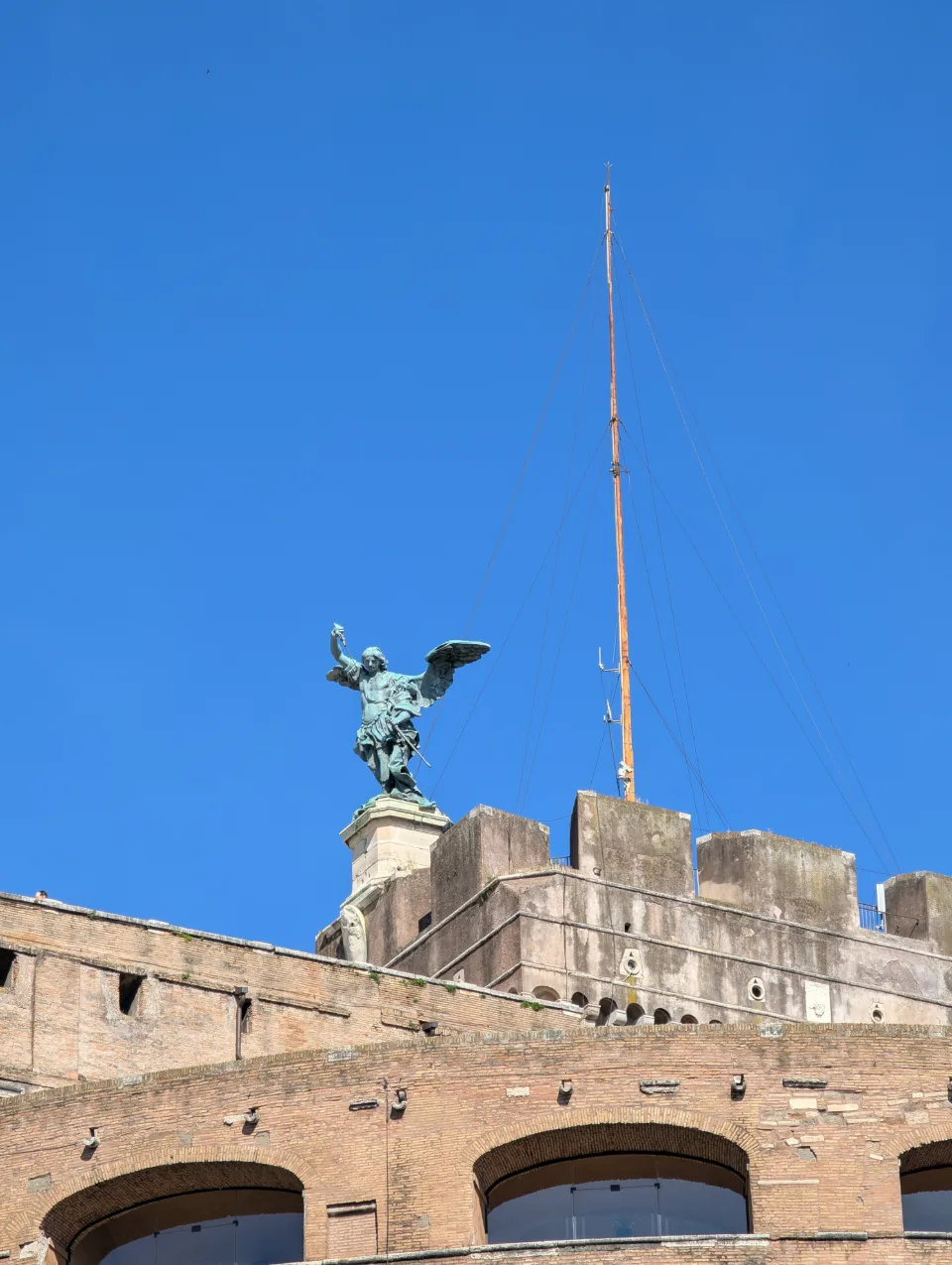 Angel statue atop Castel Sant'Angelo against a blue morning sky