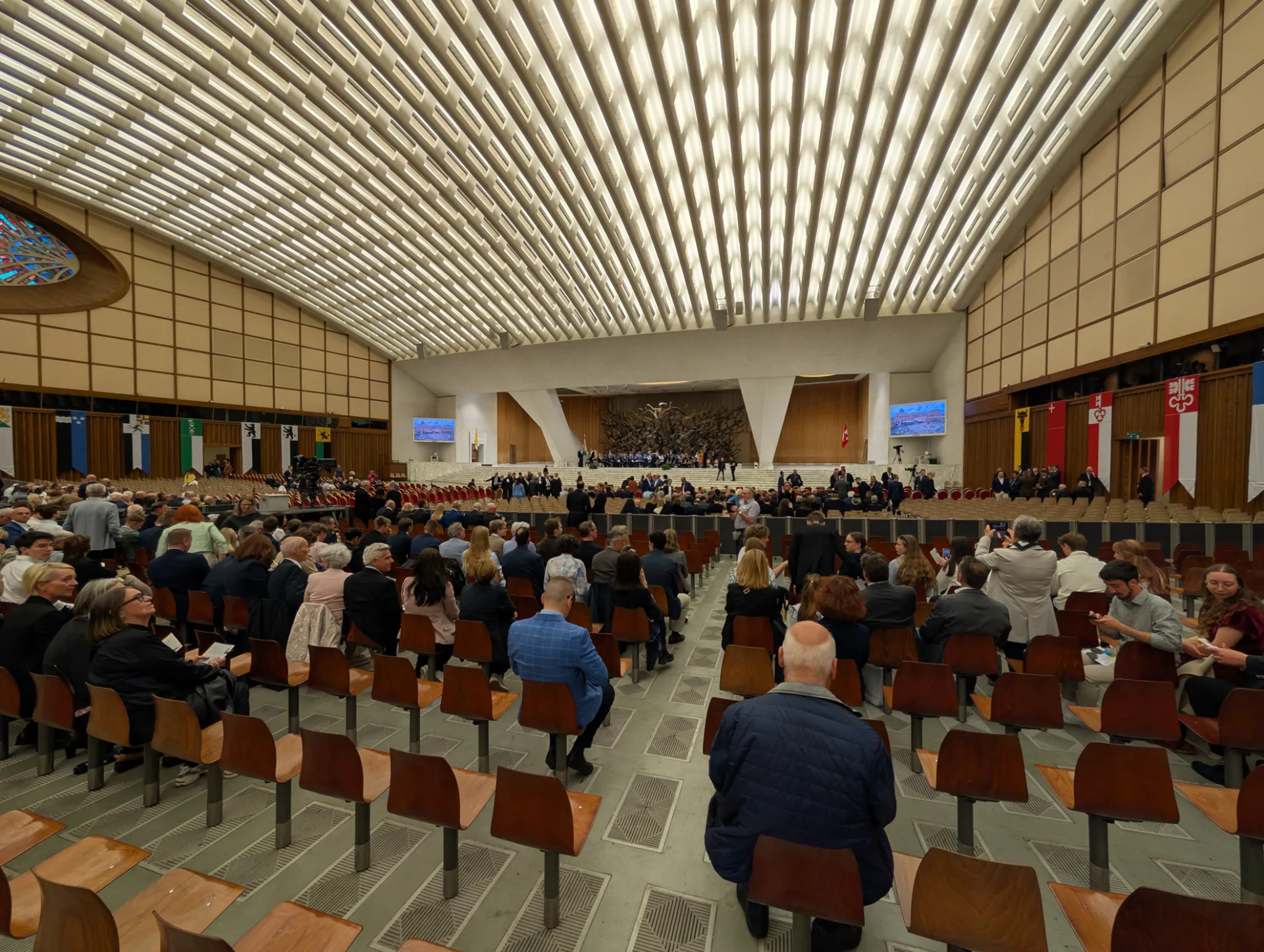 Paul VI Audience Hall — rows of chairs and the red-yellow helmets of the Swiss Guard at the back