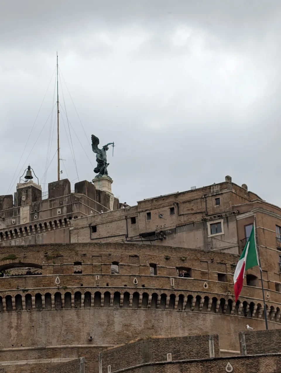 Castel Sant'Angelo under a grey sky, the Italian flag in the wind