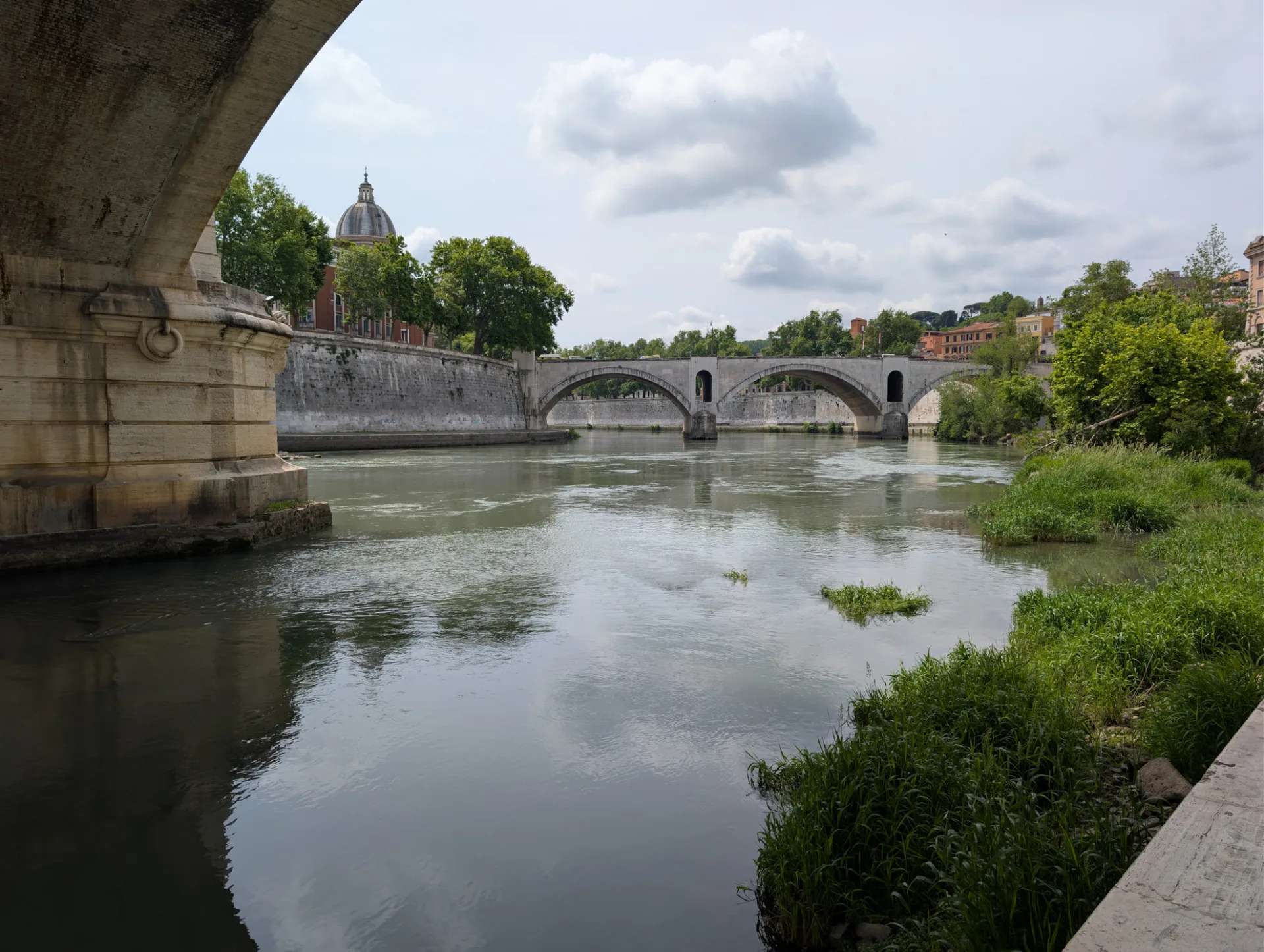 The Tiber beneath a bridge — the dome of San Giovanni Battista in the distance