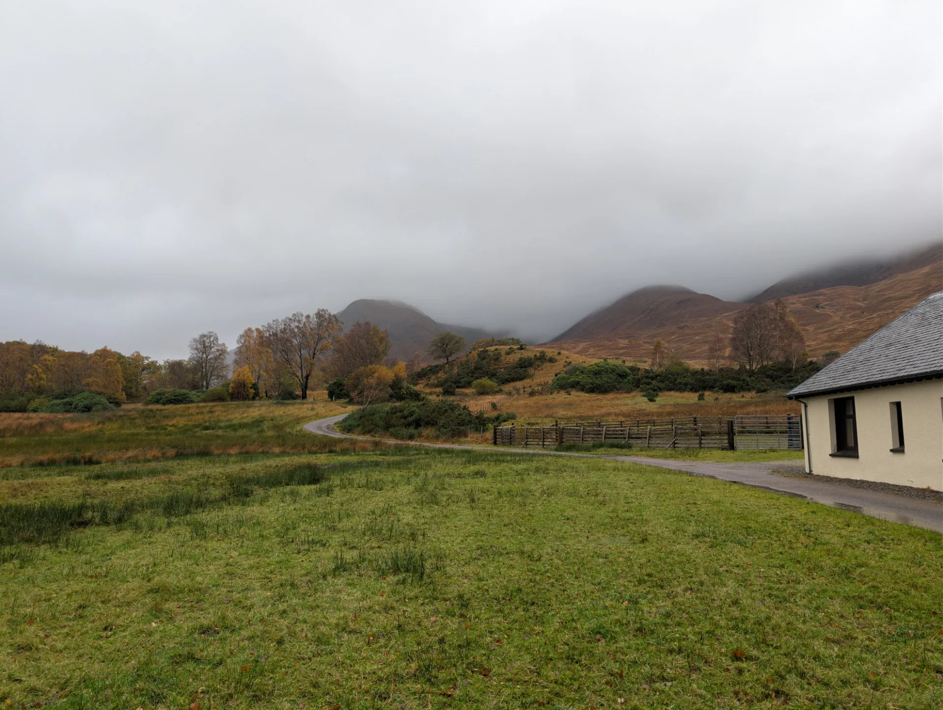 Lone cottage along the trail, mountain flanks shrouded in cloud
